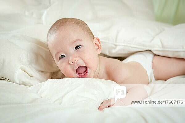 Junges gemischtrassiges chinesisches und kaukasisches Baby hat Spaß auf seiner Decke
