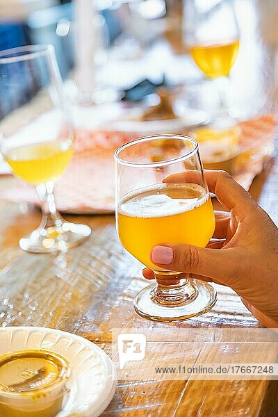 Weibliche Hand hält ein Glas Mikro-Bier an einer Bar