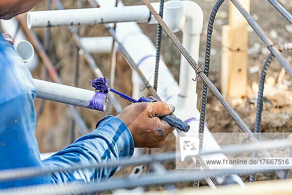 Klempner beim Auftragen von Rohrreiniger  Grundierung und Klebstoff auf PVC-Rohre auf der Baustelle