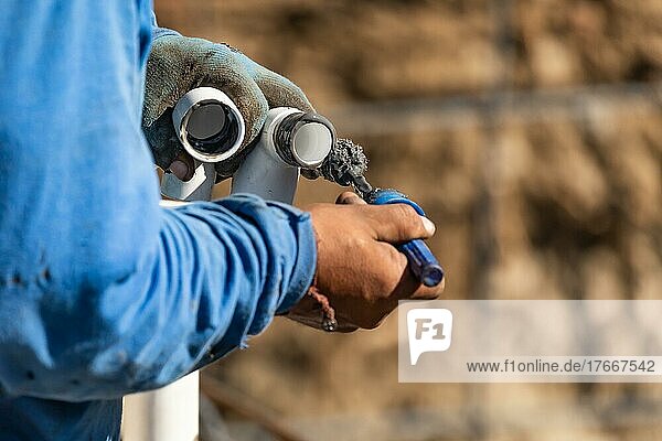 Klempner beim Auftragen von Rohrreiniger  Grundierung und Klebstoff auf PVC-Rohre auf der Baustelle