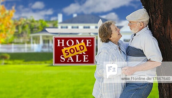 Verkauftes Immobilienschild mit glücklichem  liebevollem  älterem Paar  das sich vor einem Haus umarmt