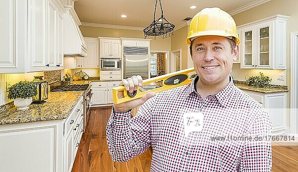 Smiling contractor with level wearing hard hat standing in custom kitchen