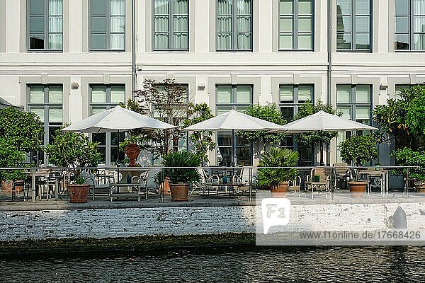 Street cafe restaurant tables with tents along canal in Bruges  Belgium  Europe