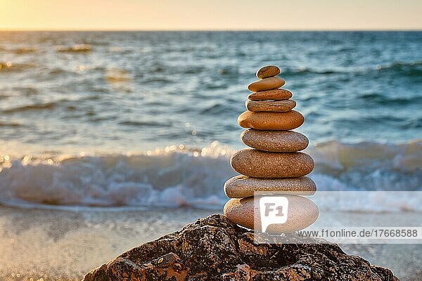 Concept of balance and harmony  Cairn stack of stones pebbles cairn on the beach coast of the sea in the nature on sunset  Meditative art of stone stacking