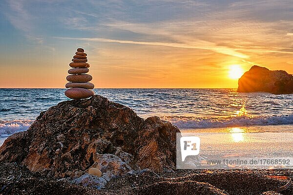 Concept of balance and harmony  Cairn stack of stones pebbles cairn on the beach coast of the sea in the nature on sunset  Meditative art of stone stacking