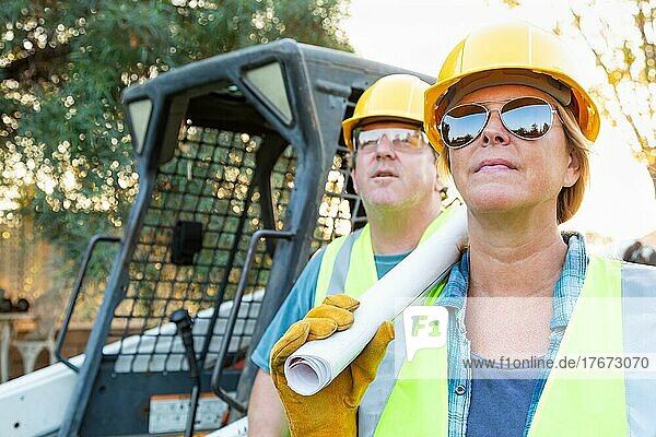 Männliche und weibliche Arbeiter mit technischen Plänen auf der Baustelle