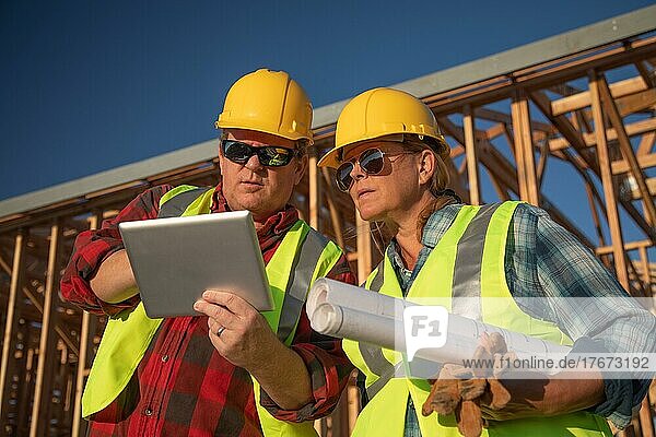Männliche und weibliche Bauarbeiter  die auf der Baustelle ein Computerpad benutzen