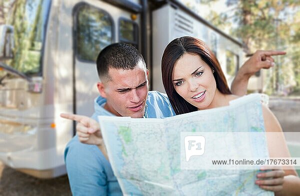 Junges verlorenes und verwirrtes Militärpaar  das vor einem Wohnmobil auf eine Karte schaut