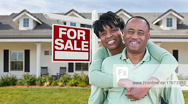 Glückliches afrikanisches amerikanisches Paar vor einem schönen Haus und einem Immobilienschild zum Verkauf