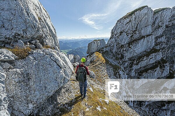 Wanderer mit Kletterhelm  auf Wanderweg an einem Grat  Ausblick auf Berglandschaft  hinten felsiger Bergkamm  Nuaracher Höhenweg  Loferer Steinberge  Tirol  Österreich  Europa