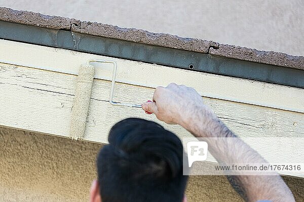 Professioneller Maler verwendet eine kleine Rolle zum Streichen der Hausfassade