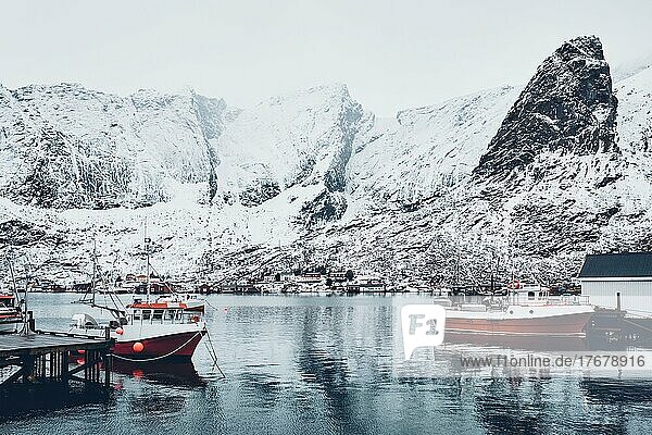 Fischerdorf Reine auf den Lofoten mit roten Rorbu-Häusern im Winter mit Schnee und Fischerbooten. Norwegen
