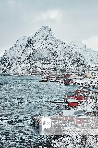 Fischerdorf Reine auf den Lofoten mit roten Rorbu-Häusern im Winter mit Schnee. Norwegen