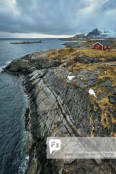 Klippe mit traditionellem roten Rorbu-Haus auf der Insel Litl-Toppoya auf den Lofoten  Norwegen im Winter