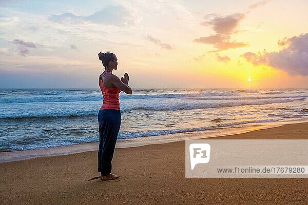 Frau macht Ashtanga Vinyasa Yoga asana Tadasana Samasthiti Yoga-Haltung am Strand