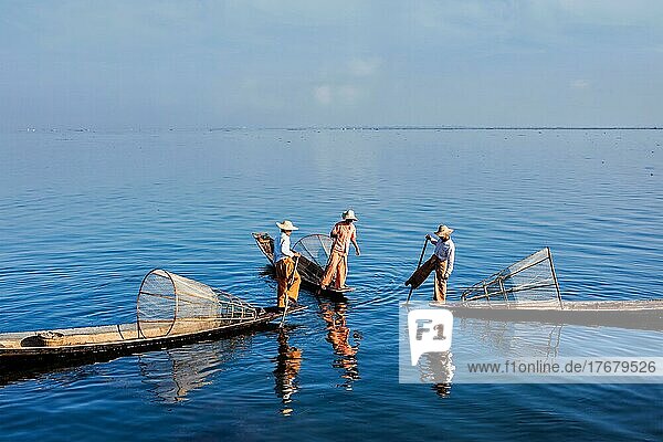 Myanmar Reiseattraktion Wahrzeichen  drei traditionelle birmanische Fischer mit Fischernetzen auf Booten am Inle-See