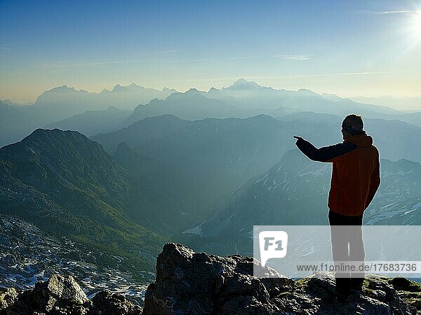 Climber at the summit of Krn 2. 244m pointing to his next target  Triglav National Park  Julian Alps  Slovenia  Europe