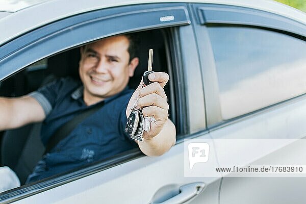 A man in his vehicle showing his new car keys  a happy guy showing the keys of his new car  Person in his vehicle showing his car keys  vehicle rental concept