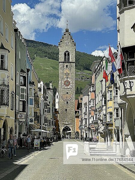 Blick auf Zwölferturm in historische Neustadt von Sterzing  im Vordergrund Sankt-Johann-Nepomuk-Brunnen  darüber italienische Nationalflagge  Flagge von Südtirol  Sterzing  Südtirol  Italien  Europa