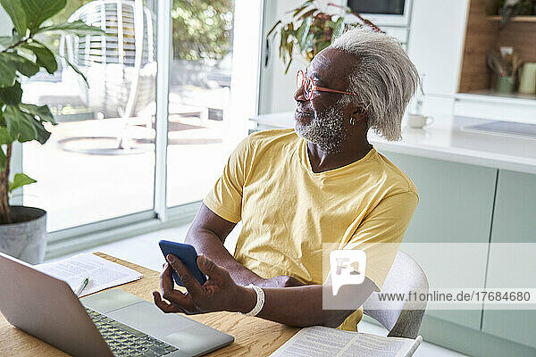 Senior man holding smart phone and looking away