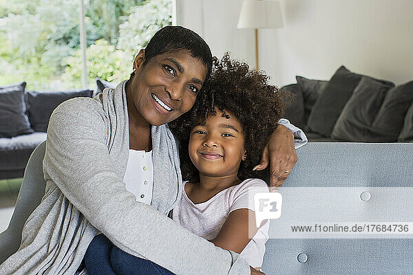 Happy grandmother and granddaughter sitting on sofa
