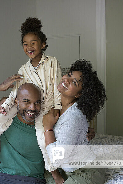 Smiling family sitting together on bed