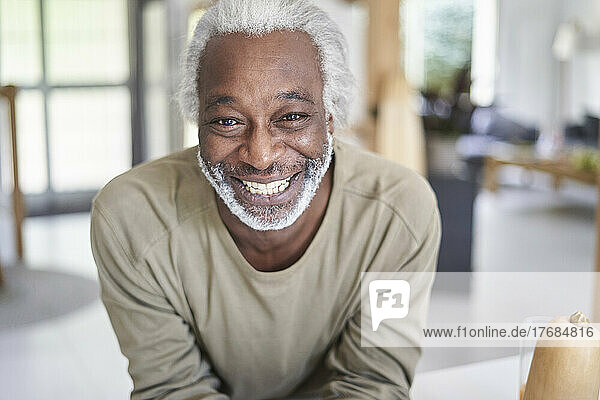 Smiling senior man leaning on kitchen worktop