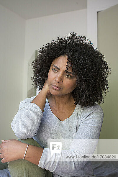 Thoughtful woman sitting in bedroom