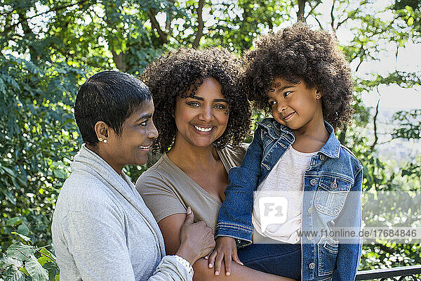 Smiling mother looking at camera while granddaughter and grandmother looking at each other