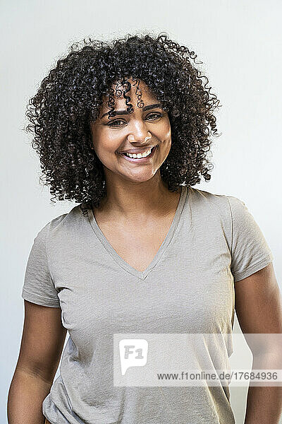 Smiling woman standing against white wall