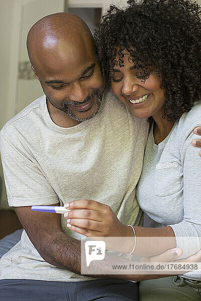Happy couple holding pregnancy test kit