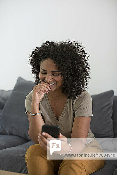 Woman using smart phone while sitting on sofa