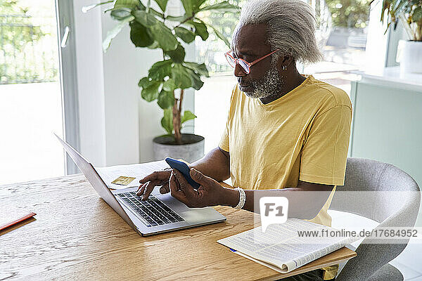 Senior man using smart phone and laptop