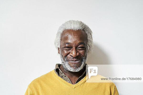 Smiling senior man standing against wall