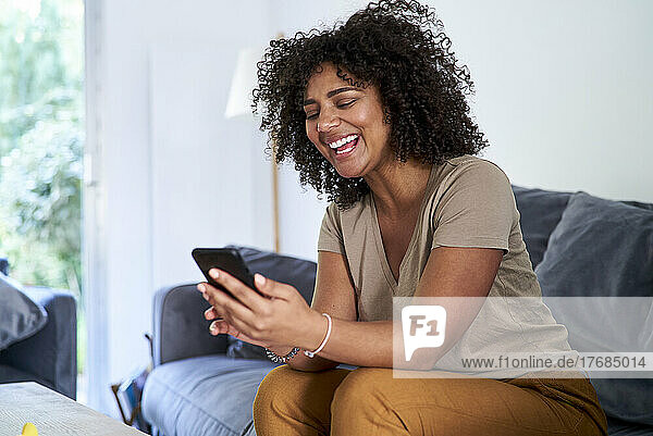 Woman using smart phone while sitting in living room