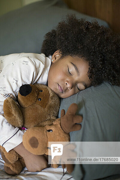 Girl sleeping with toy on bed