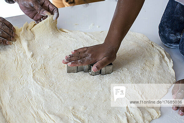 Two people rolling dough in kitchen
