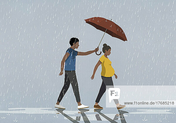 Husband holding umbrella over pregnant wife walking in rain