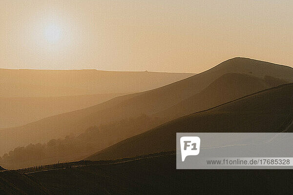 Silhouetted hills in golden sunrise landscape  Castleton  Derbyshire  England