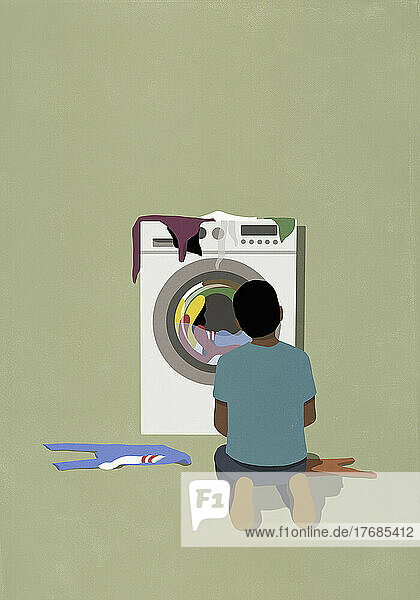 Mann kniet am Trockner und wartet darauf  dass die Wäsche trocknet