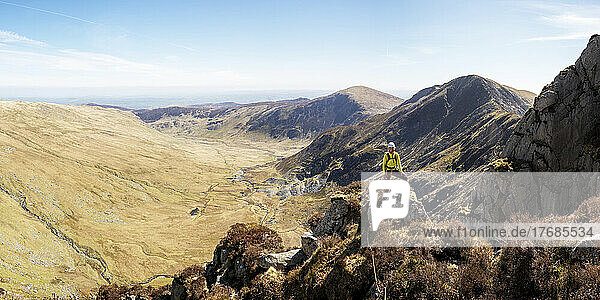 Woman standing on top of rocky cliff at sunny day
