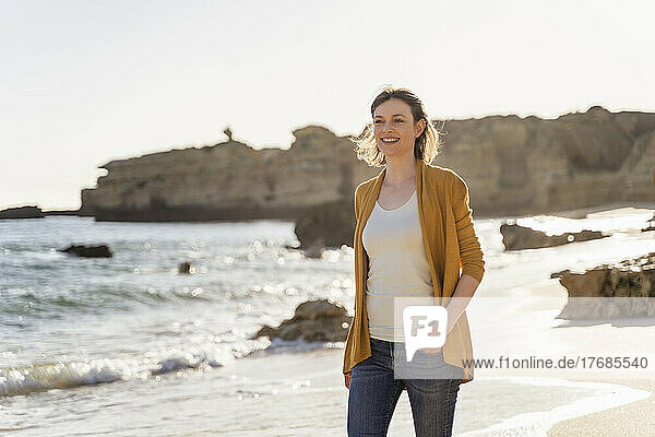 Smiling woman walking at beach on sunny day