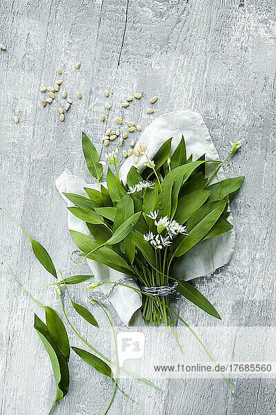 Studio shot of fresh ramson leaves and pine nuts lying against wooden surface