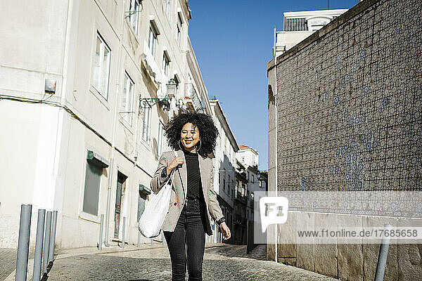 Smiling young woman walking on footpath