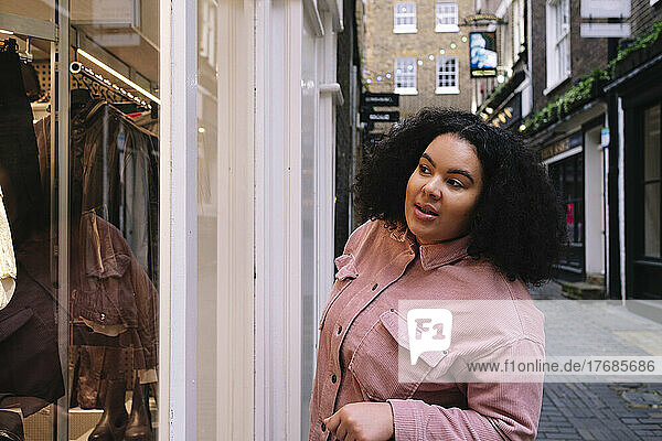 Young woman with curly hair doing window shopping