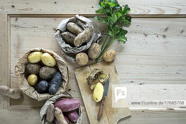 Parsley and different varieties of raw potatoes on rustic wooden background
