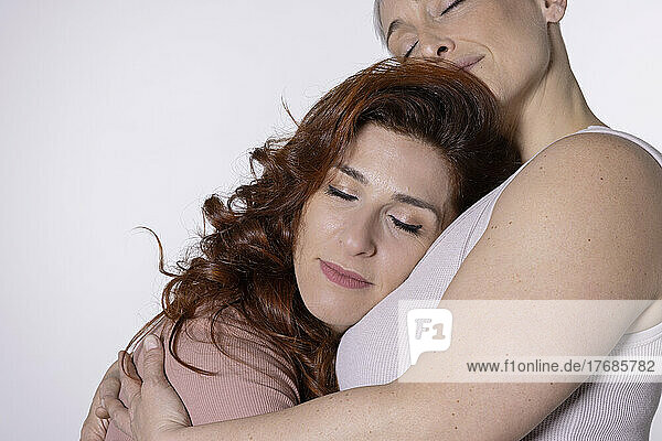 Women hugging each other against white background