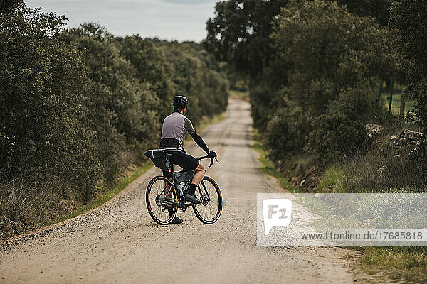 Cyclist with bicycle standing on gravel road