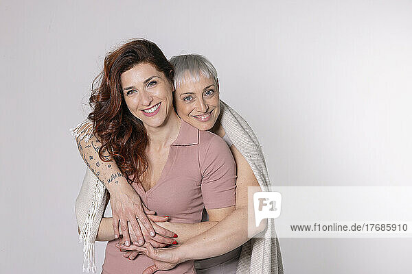 Happy friends with blanket standing against white background