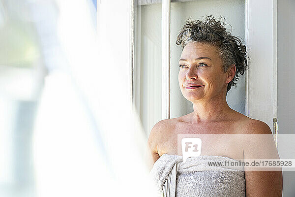 Smiling mature woman with short hair wearing towel at home